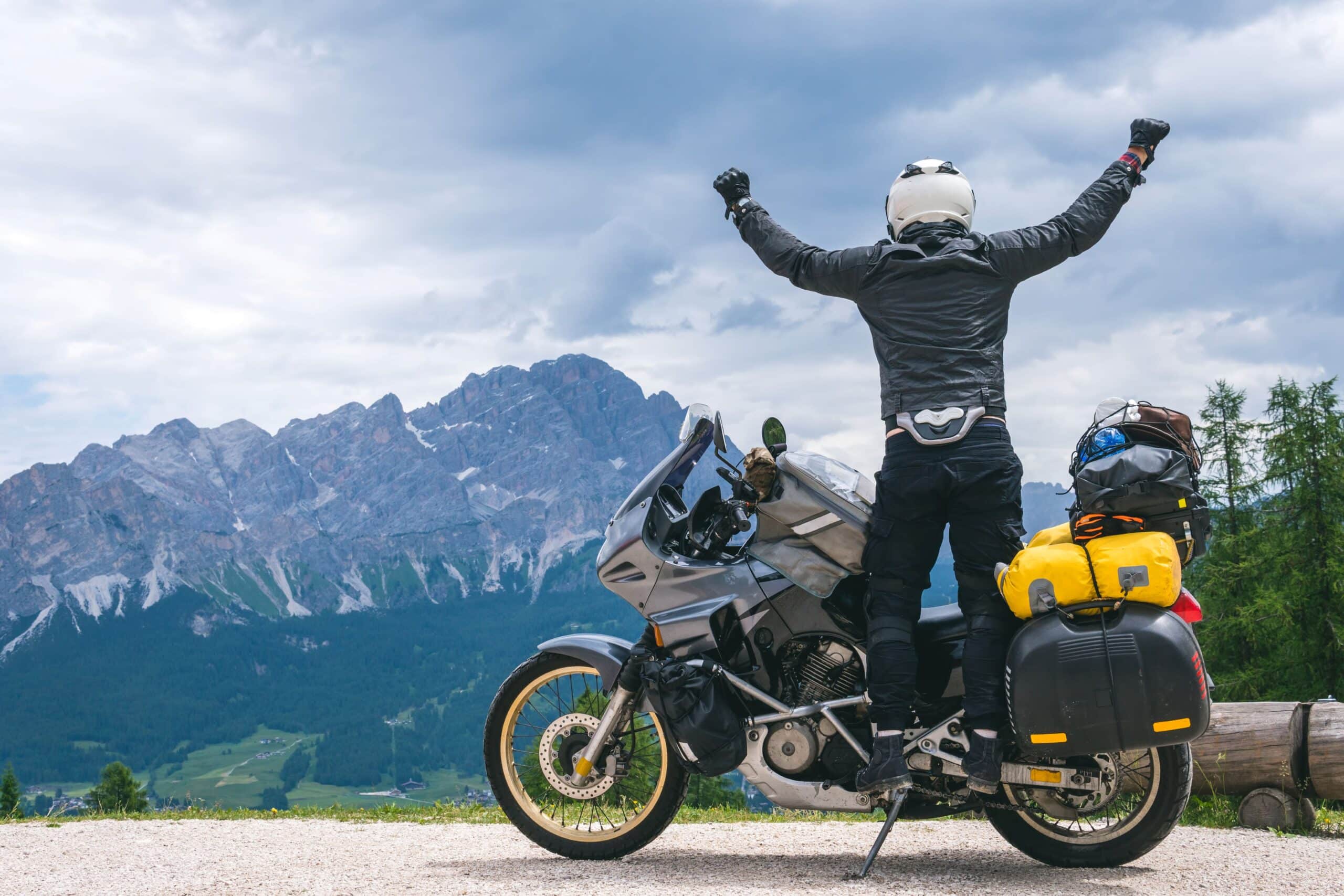 Honda NT-1100 DCT Zubehör auf Tour: Motorradfahrer mit Reisegepäck in den Bergen, beide Arme ausgestreckt