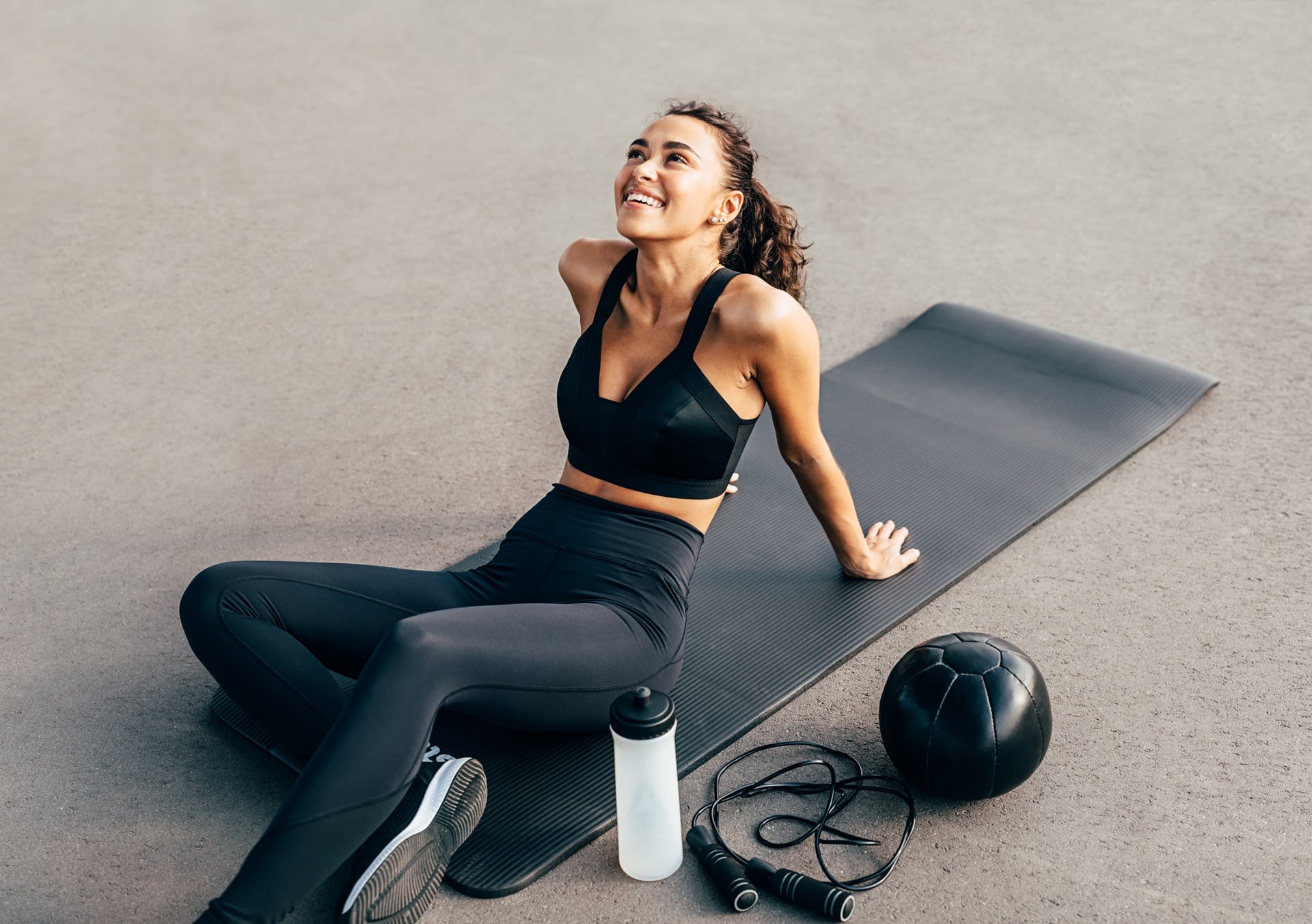 Frau macht Trainingspause auf Matte mit Sportzubehör | Ponytail Extensions

